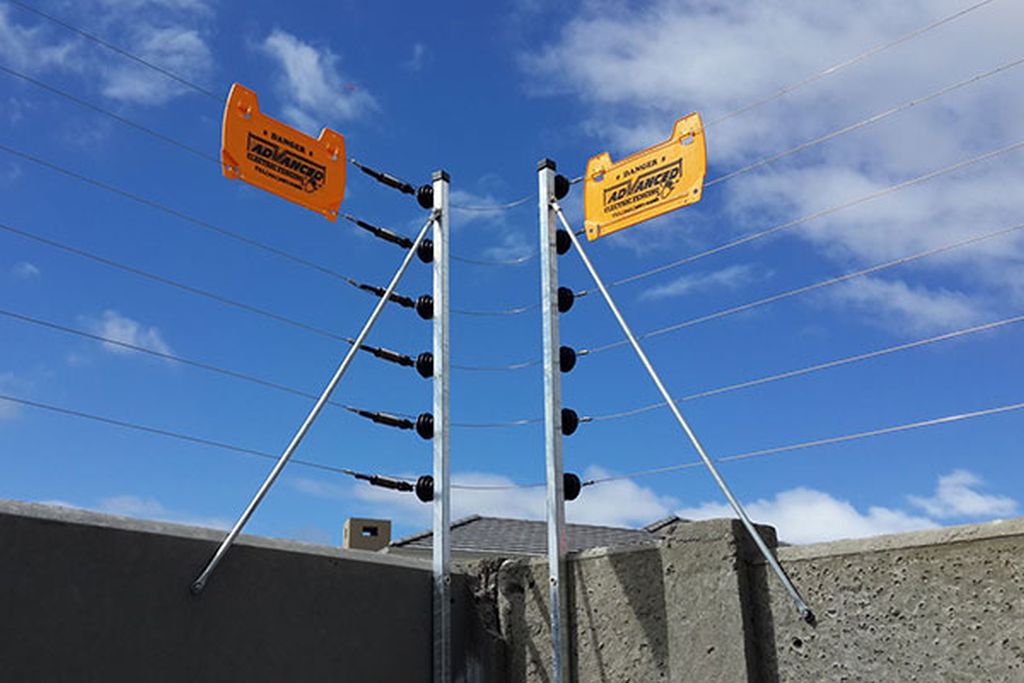 Electric fencing — wall-top strands with braced posts and danger signage